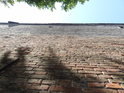 Pohled se zakloněnou hlavou na vysokou pevnostní zeď u pamětní desky Josefu II. v ulici Dukelských hrdinů.