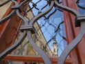 Zrcadlící se jižní věž baziliky Nanebevzetí Panny Marie a svatého Cyrila a Metoděje za mřížemi okna Stojanova gymnázia.
